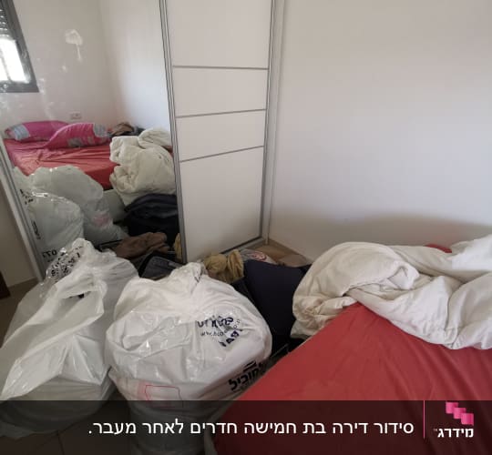 שקיות פלסטיק מלאות בגדים ליד מיטה